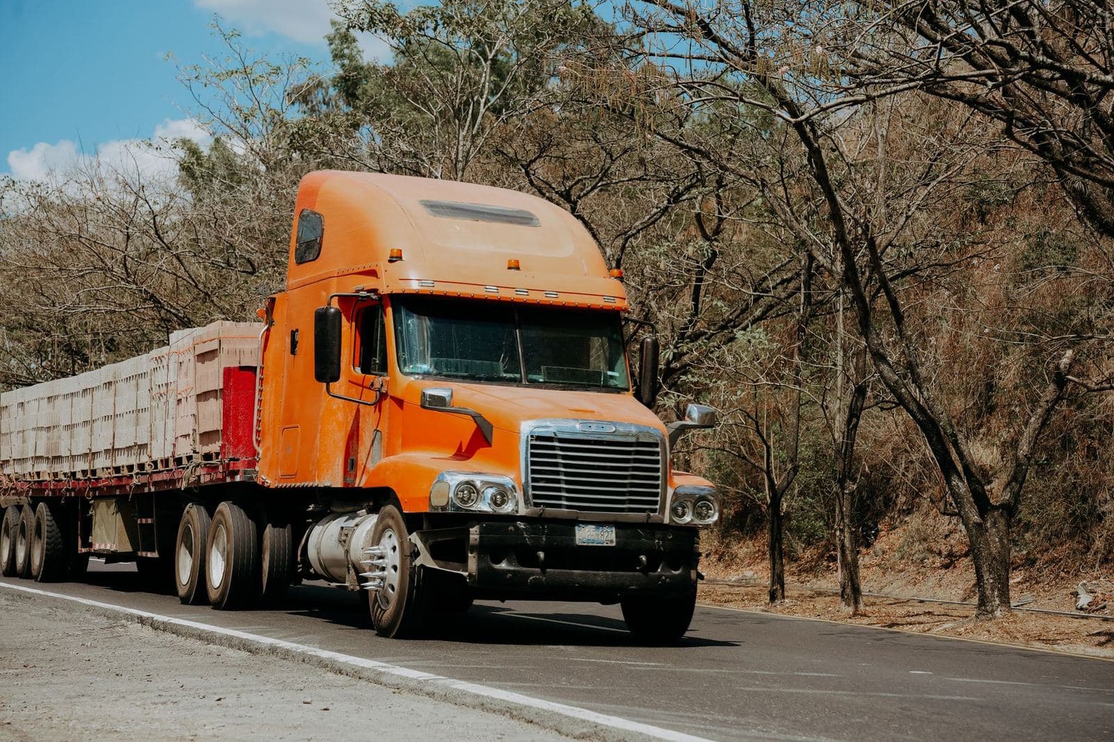 An orange Freightliner semi truck on the road