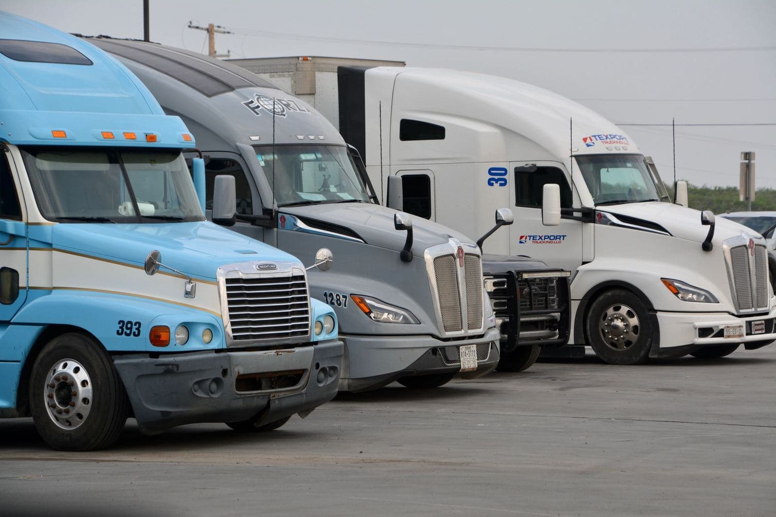 A row of parked semi trucks in Eagle Pass, Texas, a small fleet between loads