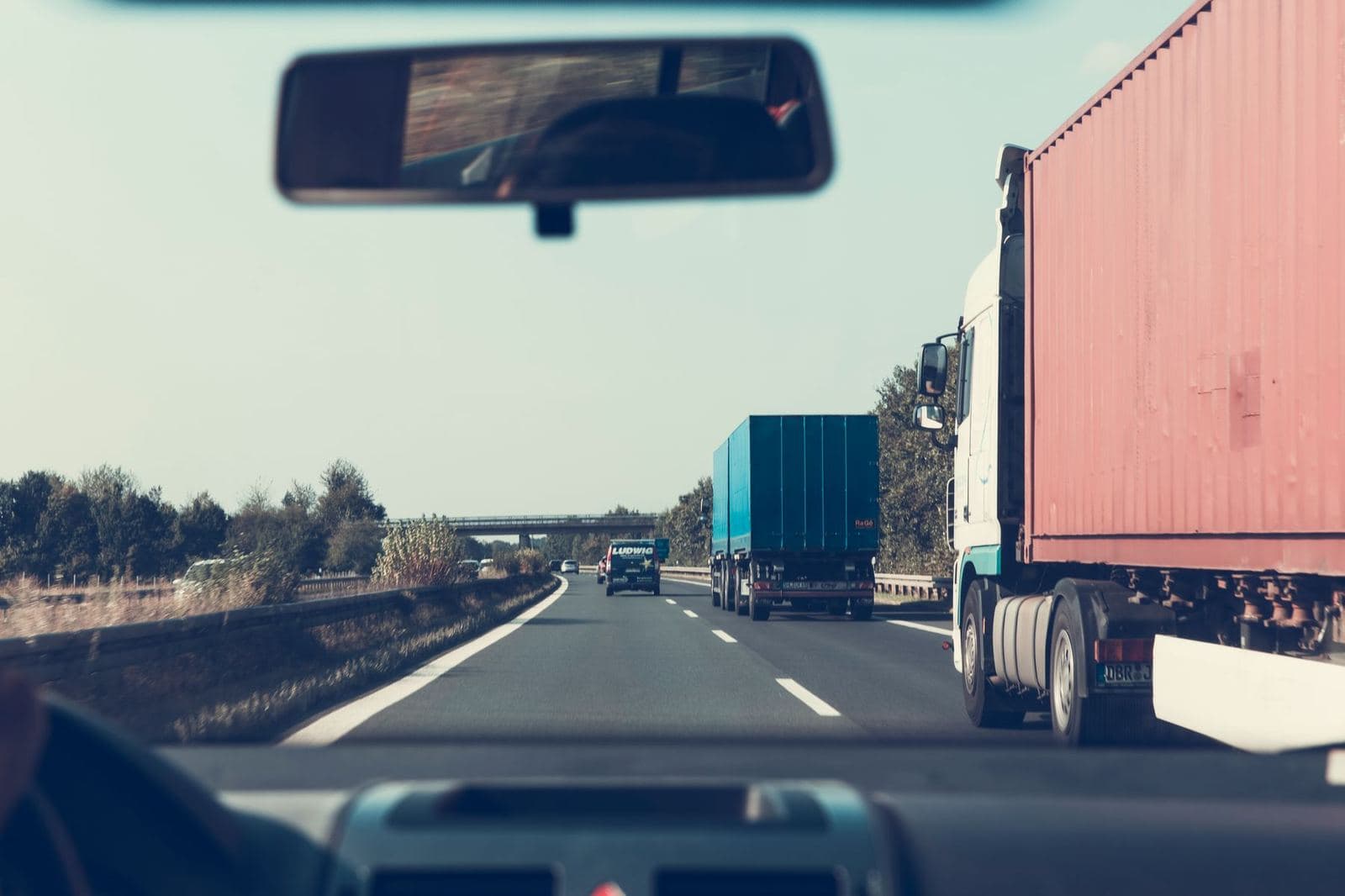 Trucks on a highway seen through a rearview mirror