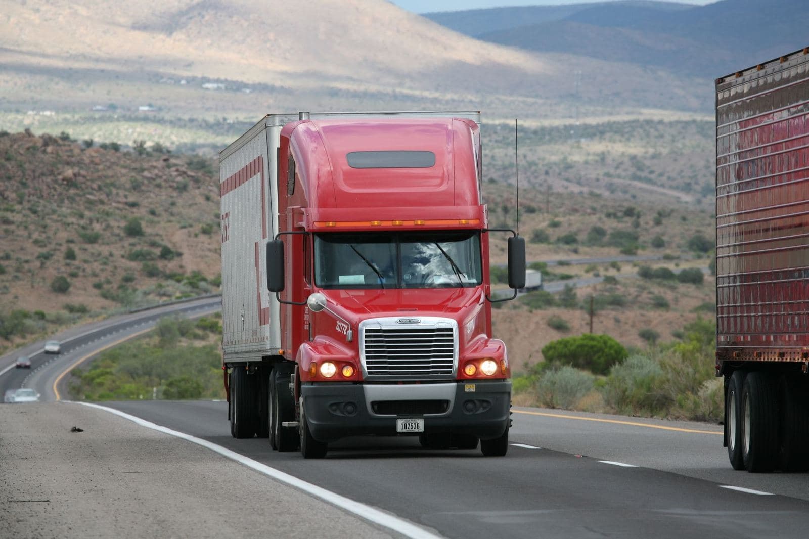 Red semi truck on a mountain highway, a loaded lane planned a day ahead