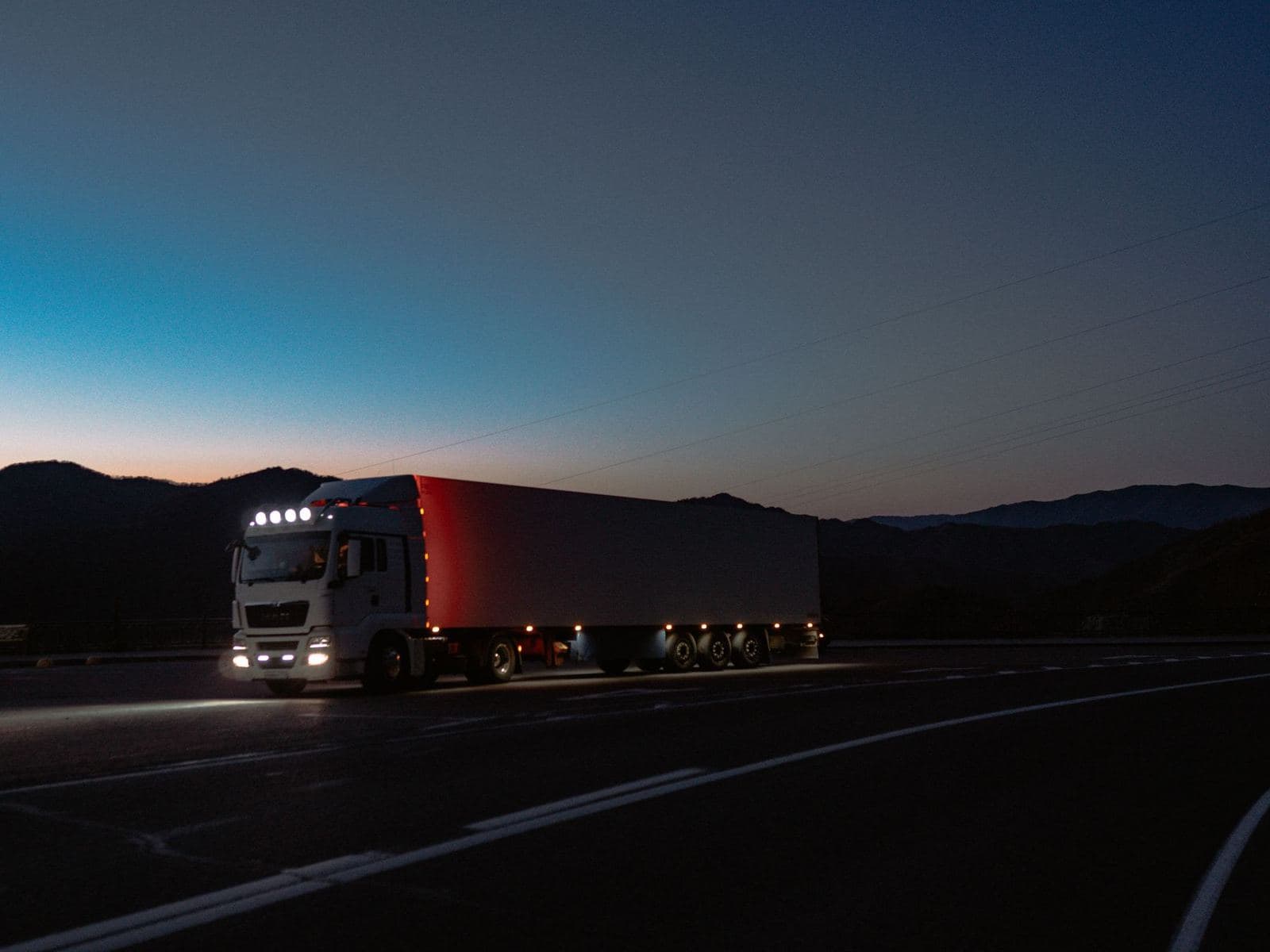 Semi truck running at night with its lights on, dispatch covering the overnight hours